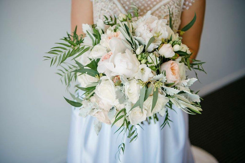Bride holding a large bouquet of ivory wedding flowers.