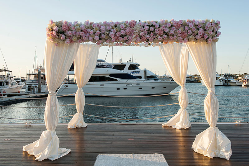 Wedding ceremony arbour set up at Southport Yacht Club with a view of the Marina..