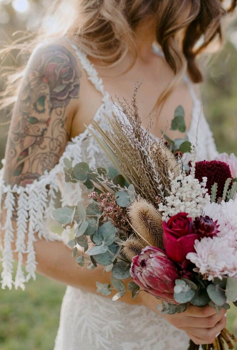 Boho bride holding a wedding bouquet of dried and native flowers.