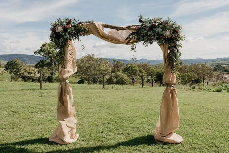 Country styled arbour with artificial native wedding flowers.