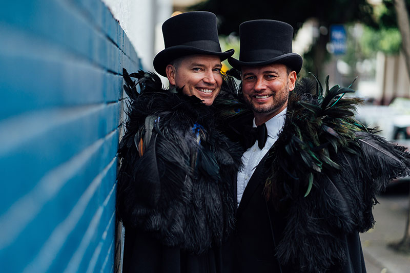 Brad and Scott getting married at Broadway Chapel, smiling in top hats and feathers.