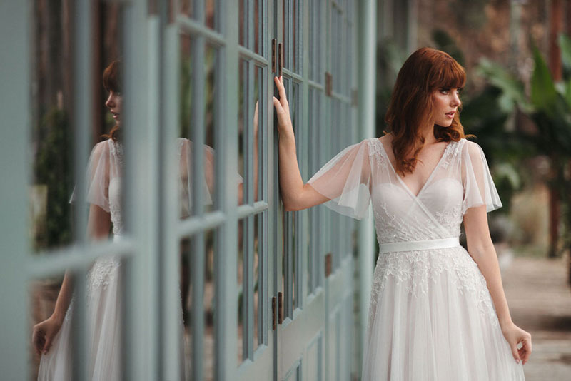 Bride in a wedding gown with flounced sleeves and flowing skirt.