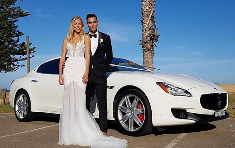 Bride and Groom standing in front of a Maserati.