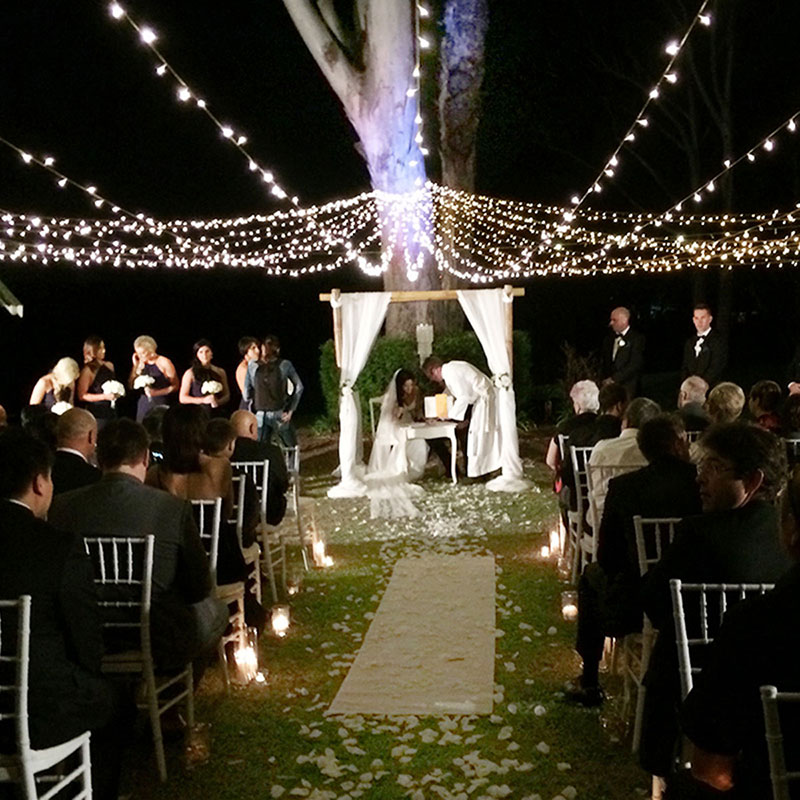 Outdoor wedding ceremony under fairylights at night.