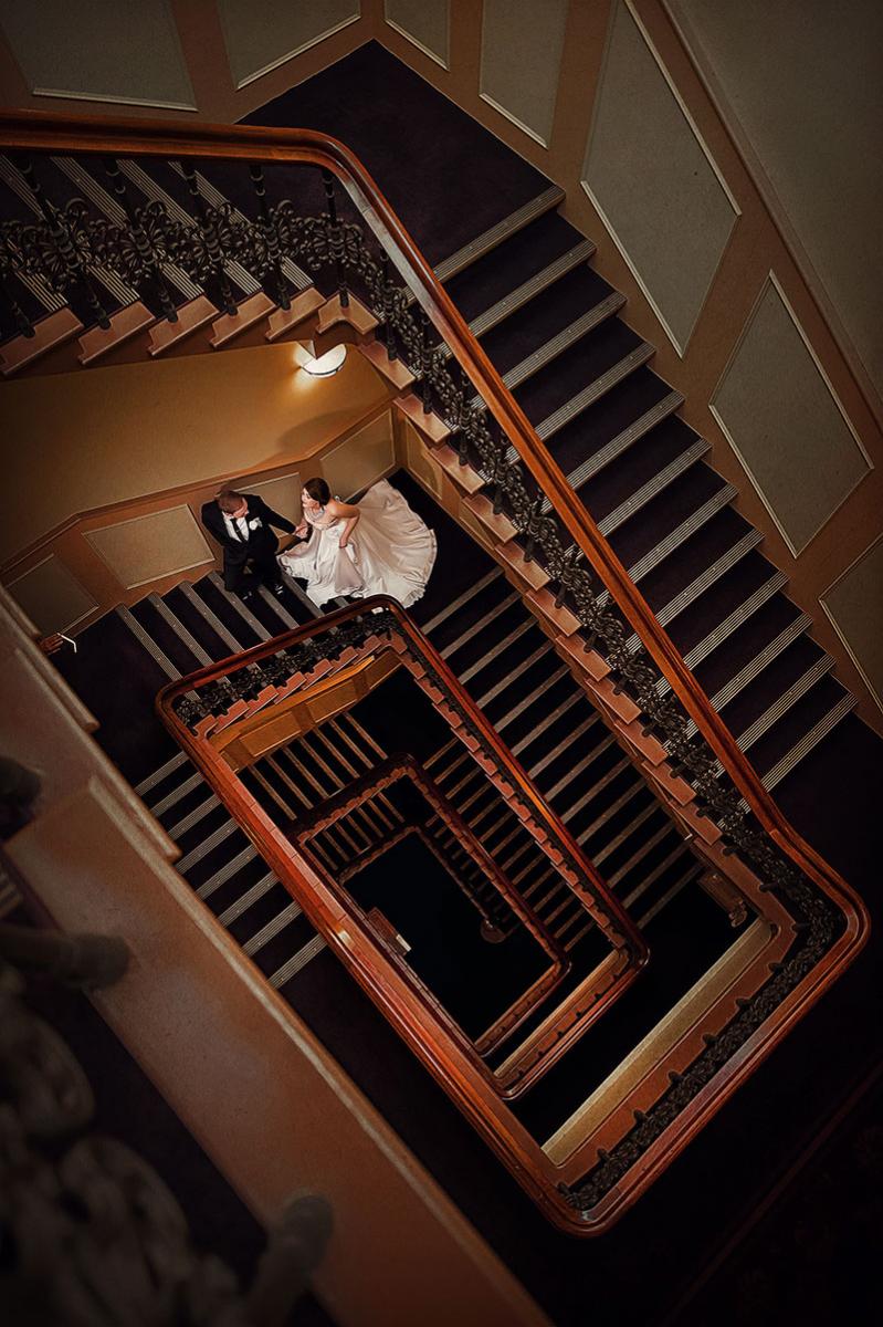 Bride and Groom walking up a spiral staircase.