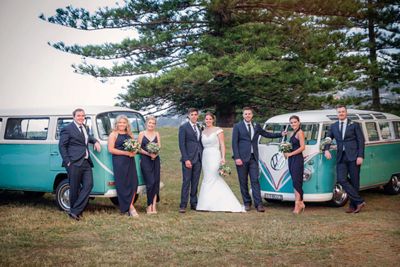 Wedding party posing in front of two Kombis.