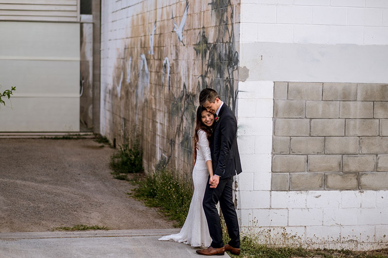 Bride and Groom leaning on a wall painted with a mural.
