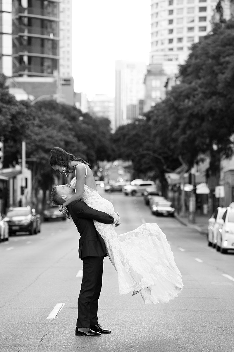 Groom picking up Bride in the middle of a city street.