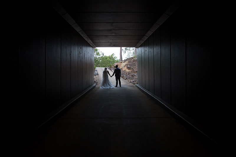 Bride and Groom walking through a tunnel.