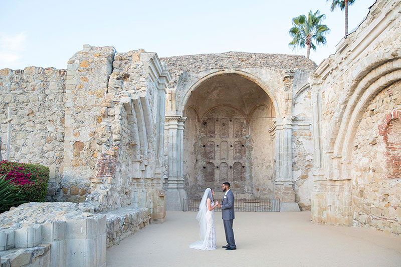 Bride and Groom stand in front of a large sandstone structure.