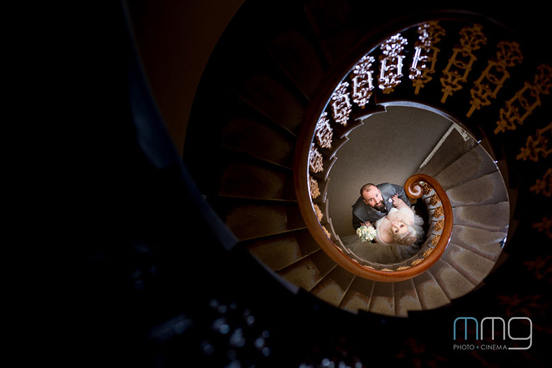 Bride and Groom look up from a spiral straircase.