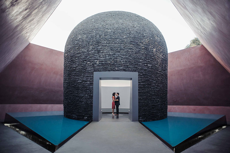 Couple stand inside a colourful, unique shaped structure.