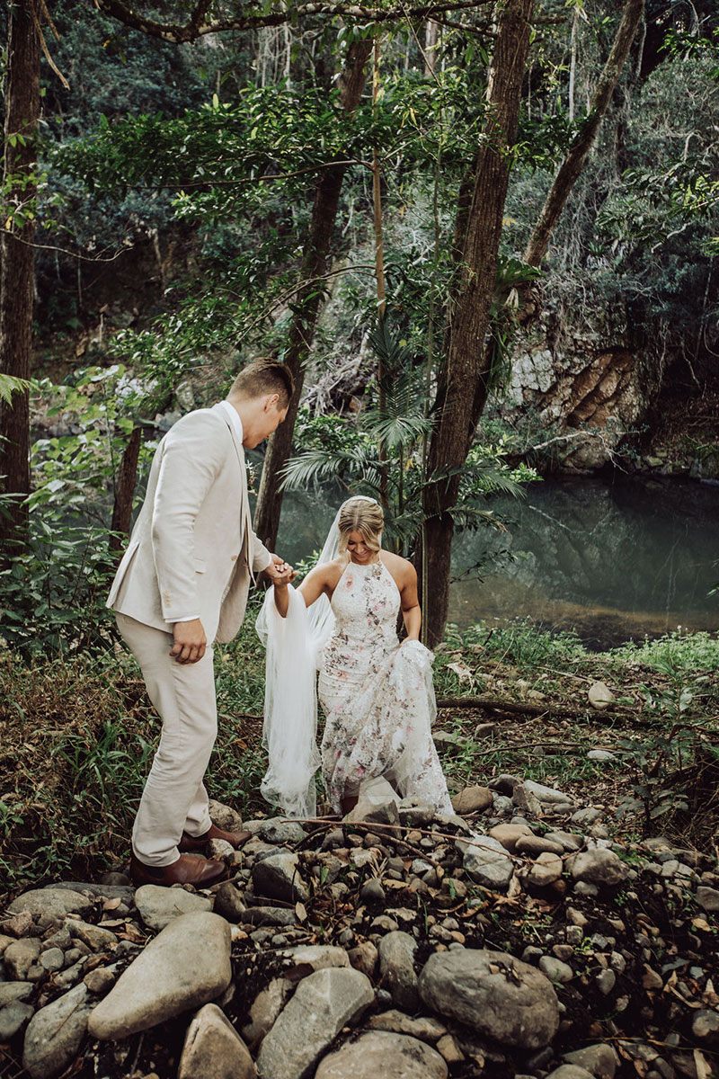 Photo by DK and Co. Photography of Groom helping Bride up a steep embankment.