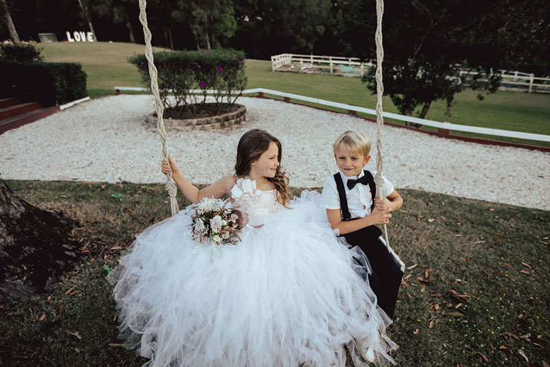 Photo by DK and Co. Photography of kids at wedding playing on swing.