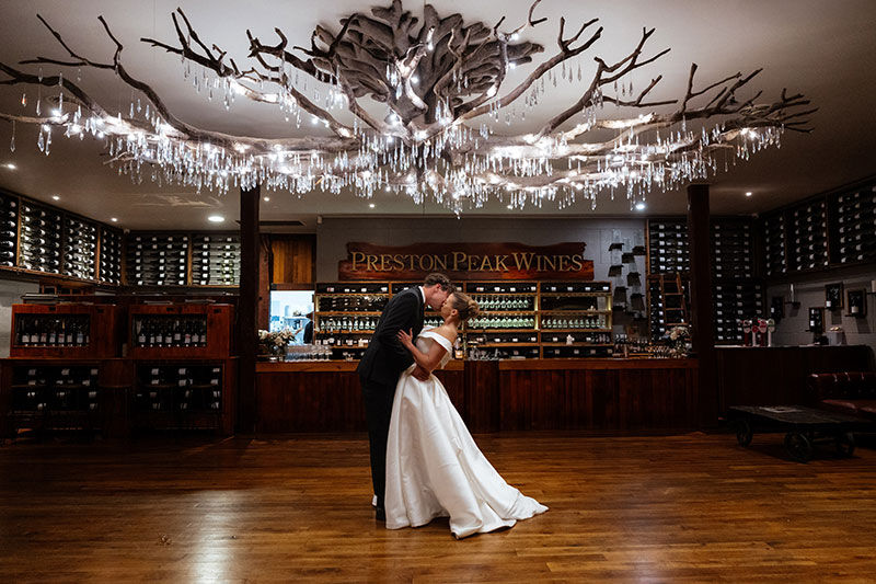 Chelsea and Christian hold eachother under the beautiful tree-shaped chandelier at Preston Peak Winery Function Centre.