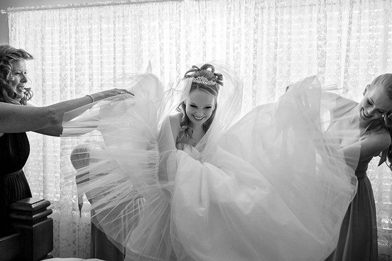 Bride getting ready with her two bridesmaids helping.