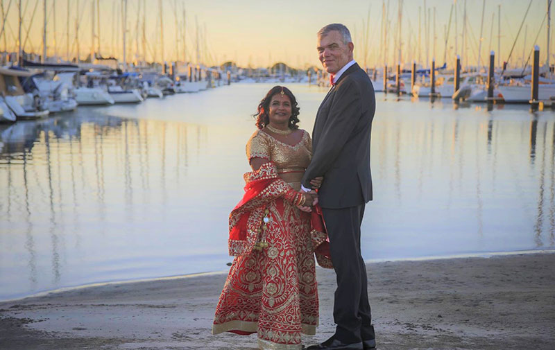 Bride in traditional wedding gown, and Groom, pose in front of the canal.