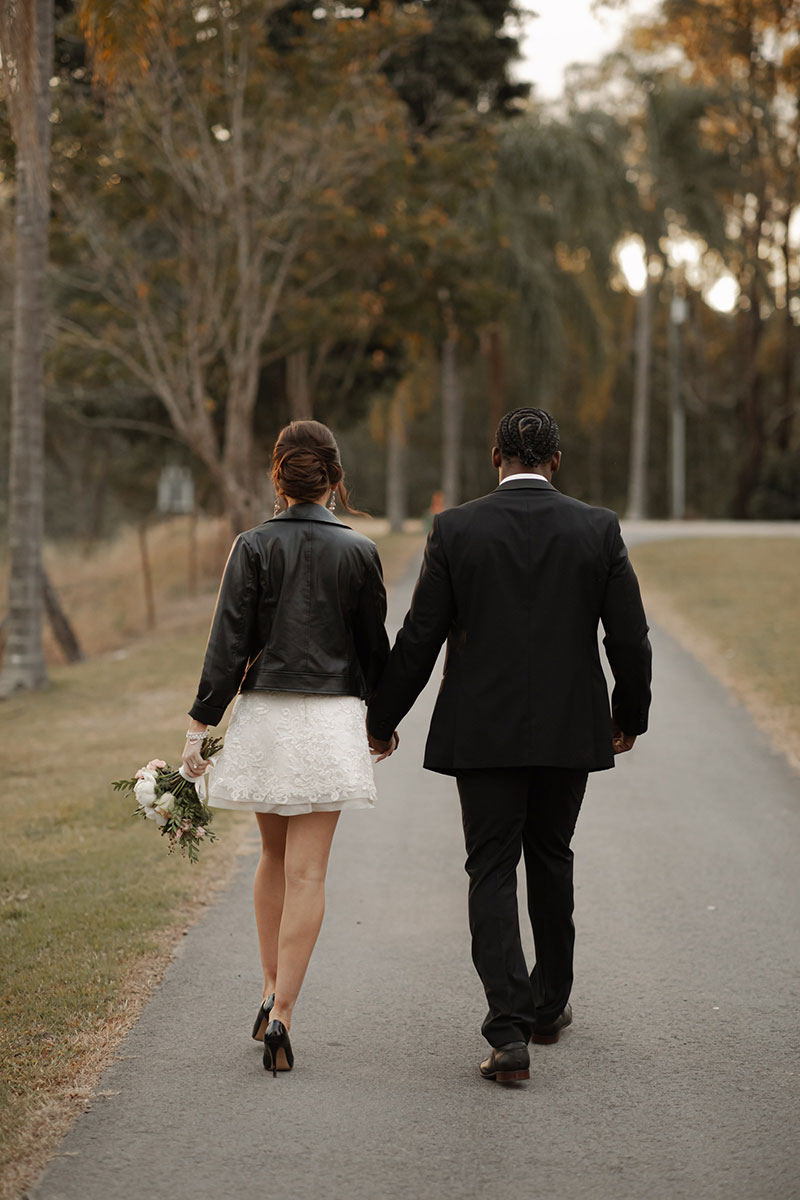 Photo by Tom Judson Photography of Bride in party dress and black stilettos and groom walking down road.
