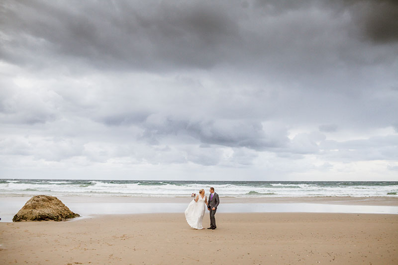 Couple on beach with clouds overhead.