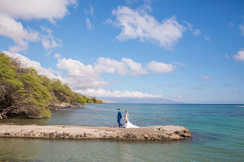 Couple walking on a beach wall on a clear day.