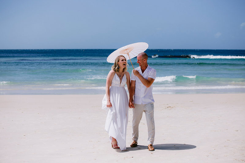 Relaxed couple sharing an umbrella at the beach.