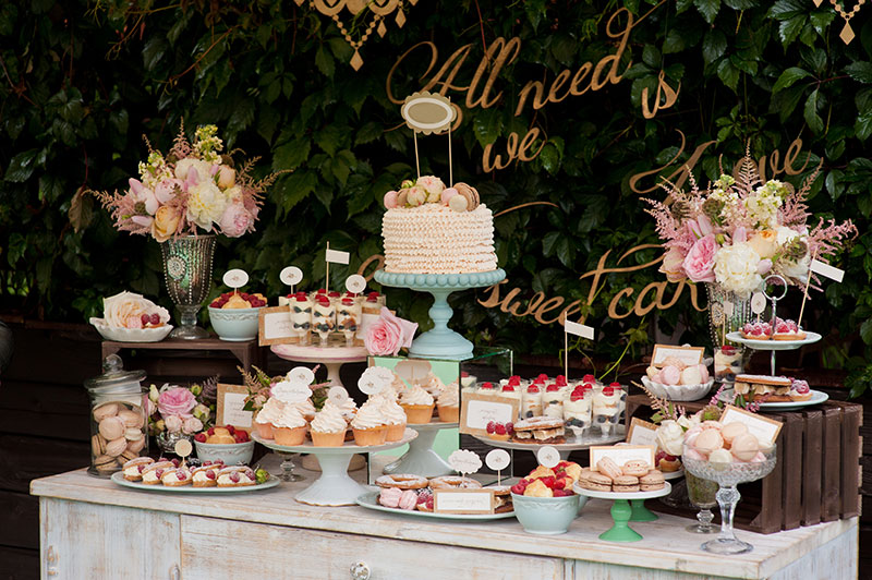 Dessert table with the wedding cake in the middle surrounded with lots of different desserts.