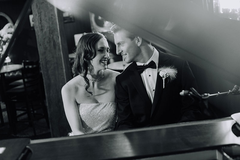 Bride and Groom sitting together at a piano.