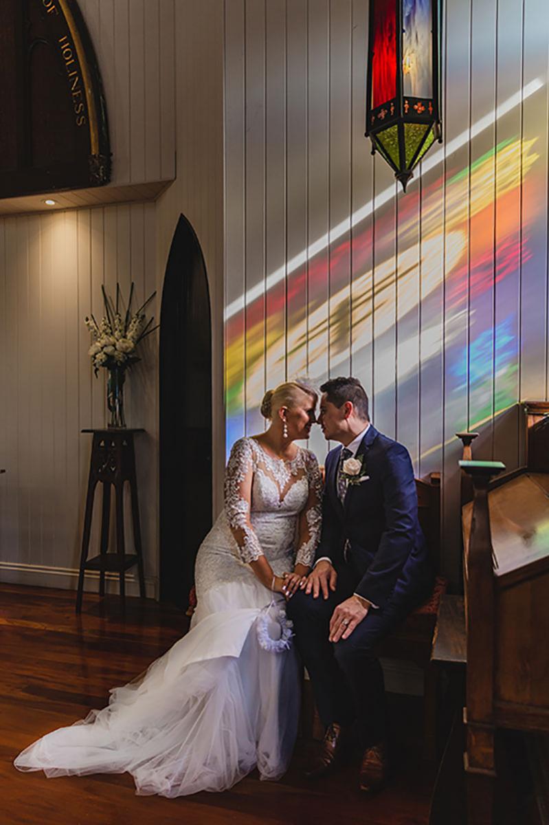 Happy bride and groom sit in the reflective light at Broadway Chapel.