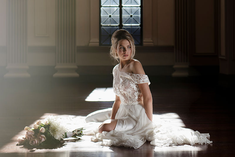 Bride sitting on floor in a two-piece Fiorenza wedding gown.