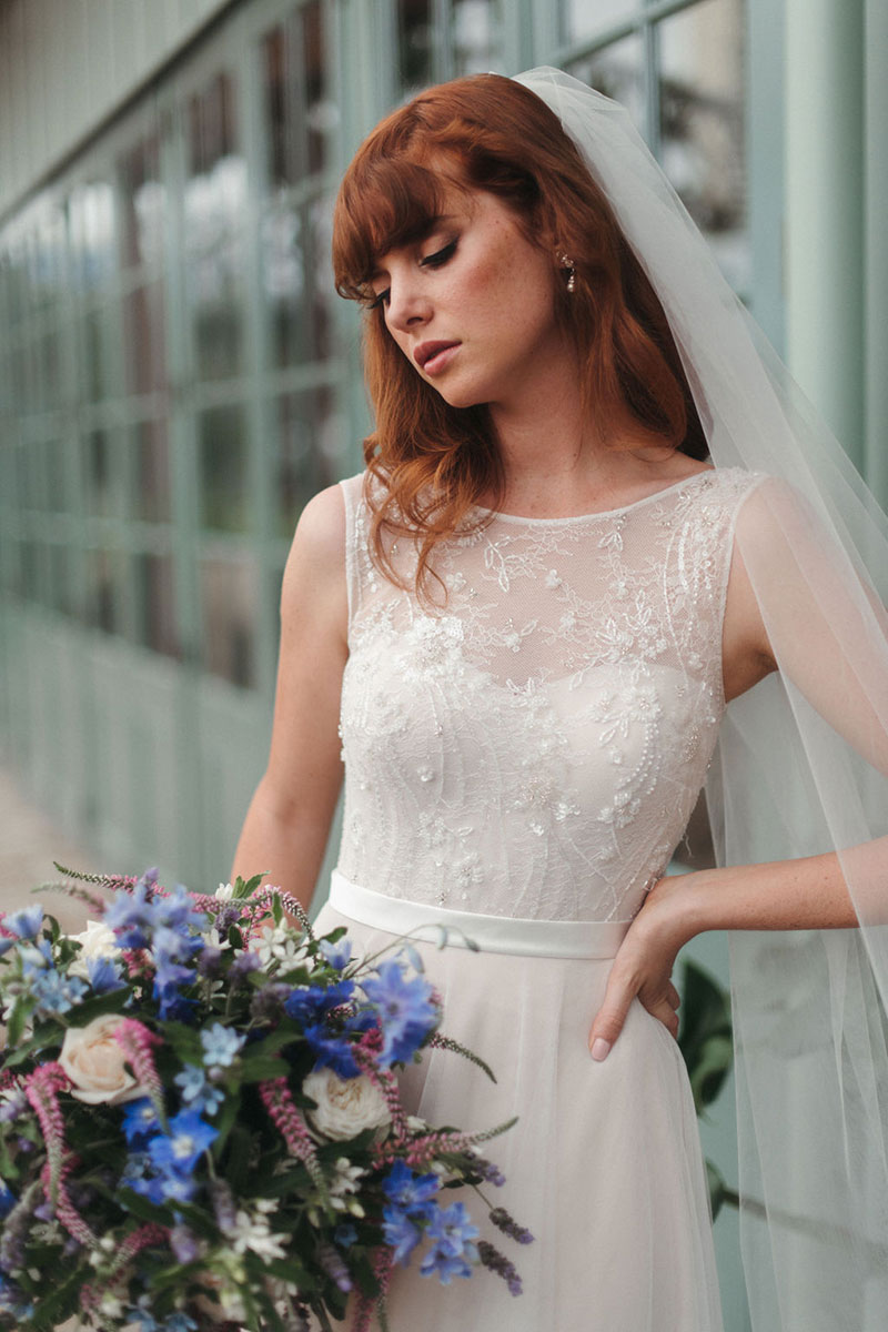 Bride holding a large flower bouquet and wearing 'Fleur' from French by Wendy Makin.