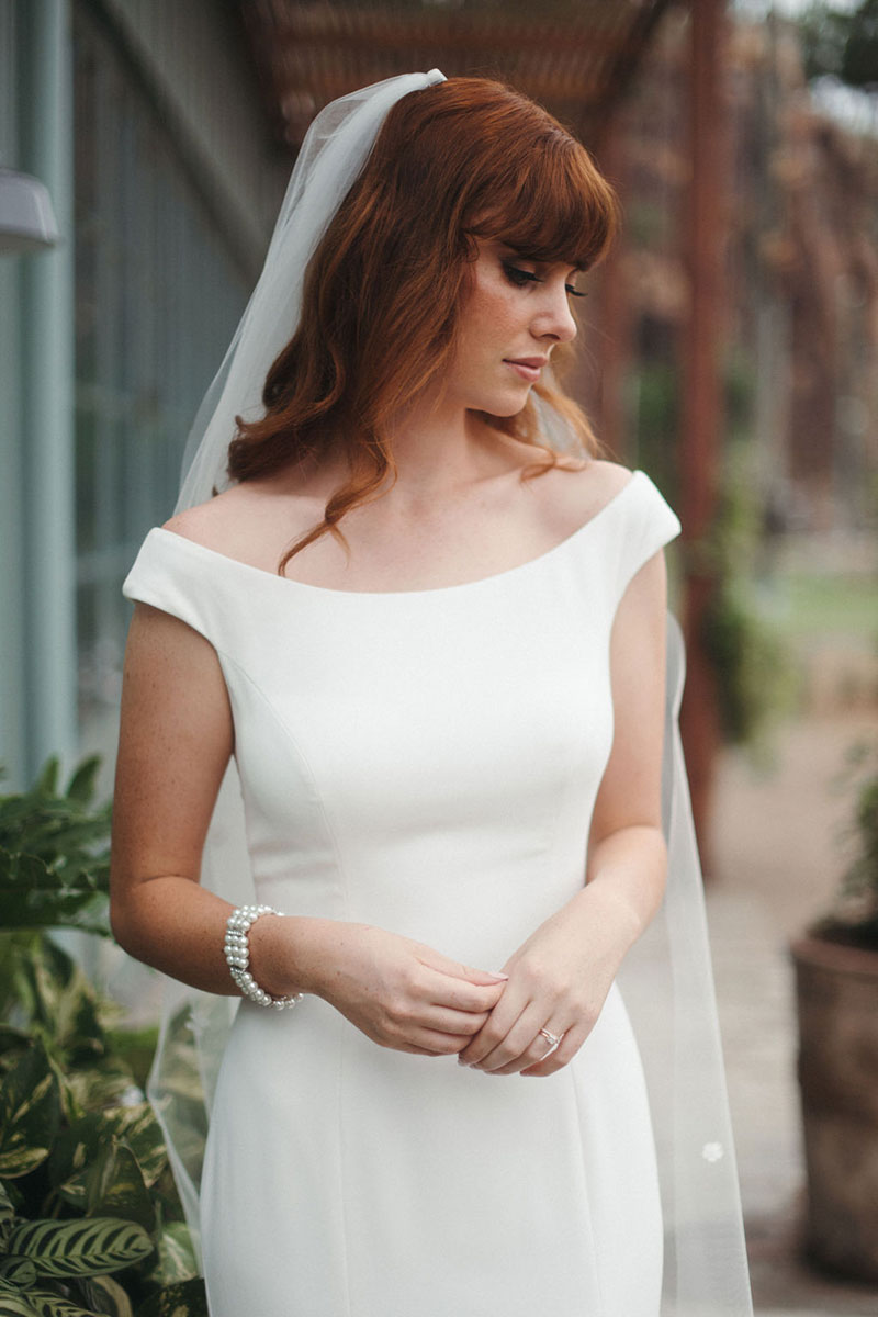 Sleek, off the shoulder wedding gown worn by bride.