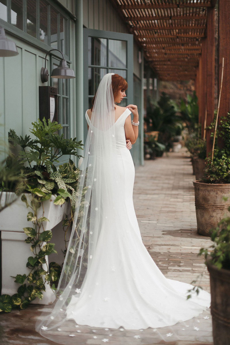 Back of a gown worn by model wearing a long veil.