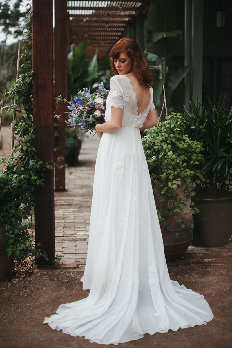 Red haired bride holding flowers in a flowing wedding gown.