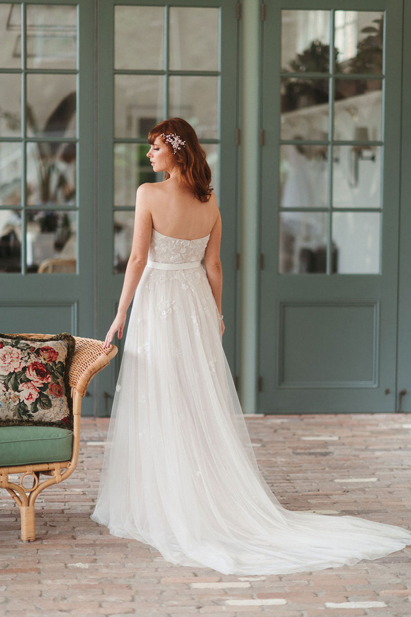 Bride in room wearing a strapless wedding gown.