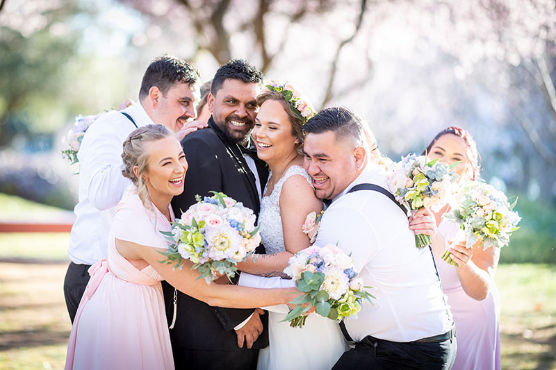 Happy wedding party huddled together and smiling.