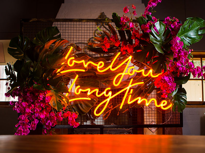 Neon wedding sign with flowers and greenery light up a room.