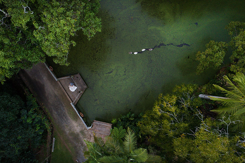 Photo of bride and groom standing on a bridge taken with a drone.