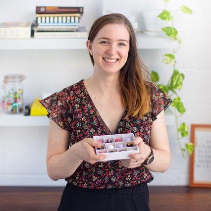 Owner of Little Cocoa, Alicia Chapman, smiling holding a giftbox of her exquisite chocolates 