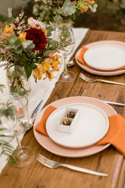 Little Cocoa chocolates in a white giftbox on table set with flowers and matching decor.