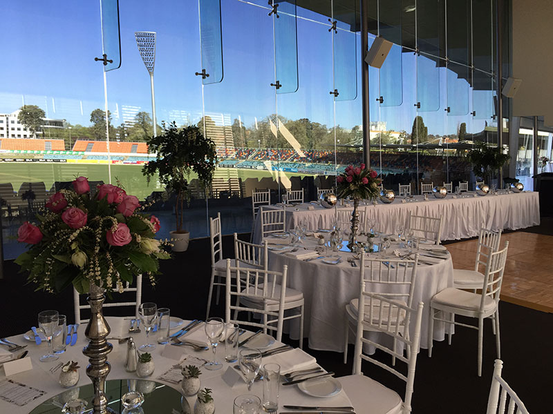Wedding set up with a backdrop of floor to ceiling windows at Manuka Oval.