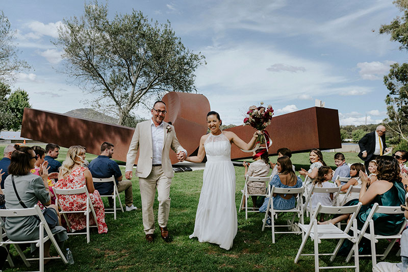 Mayumi + Sam married in front of the Knot sculpture.