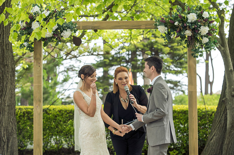Bride and Groom getting married by Nicole Penning Civil Celebrant under an outside arbour.