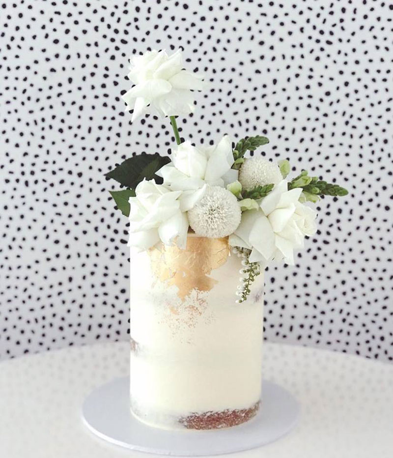 Metallic wedding cake with gold leaf detail and white roses.