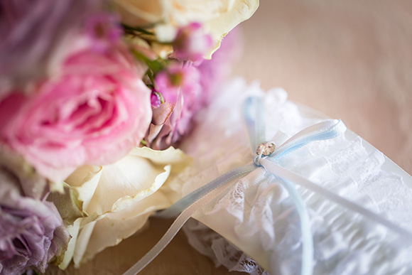 Beautiful pink flowers sitting next to a white garter with a blue ribbon.