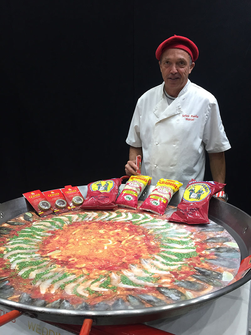 Senor Paella standing behind one of the gigantic Spanish paella pans.