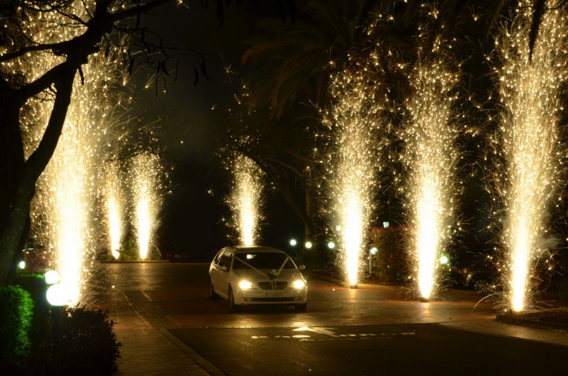 Married couple exiting reception through a line of fireworks.