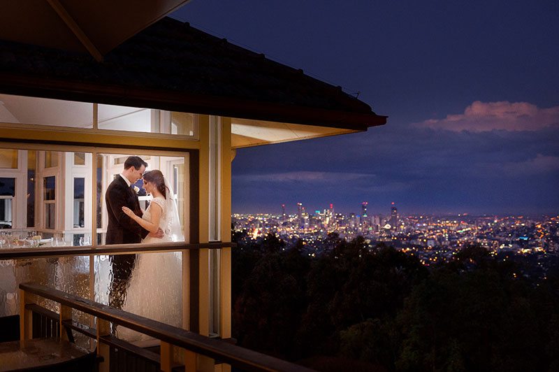Bride and Groom at the Summit Restaurant with twinkling city lights backdrop.