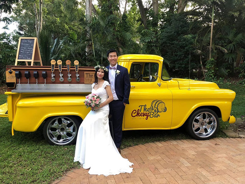 Bride and Groom pose in front of The Chevy Bar. 