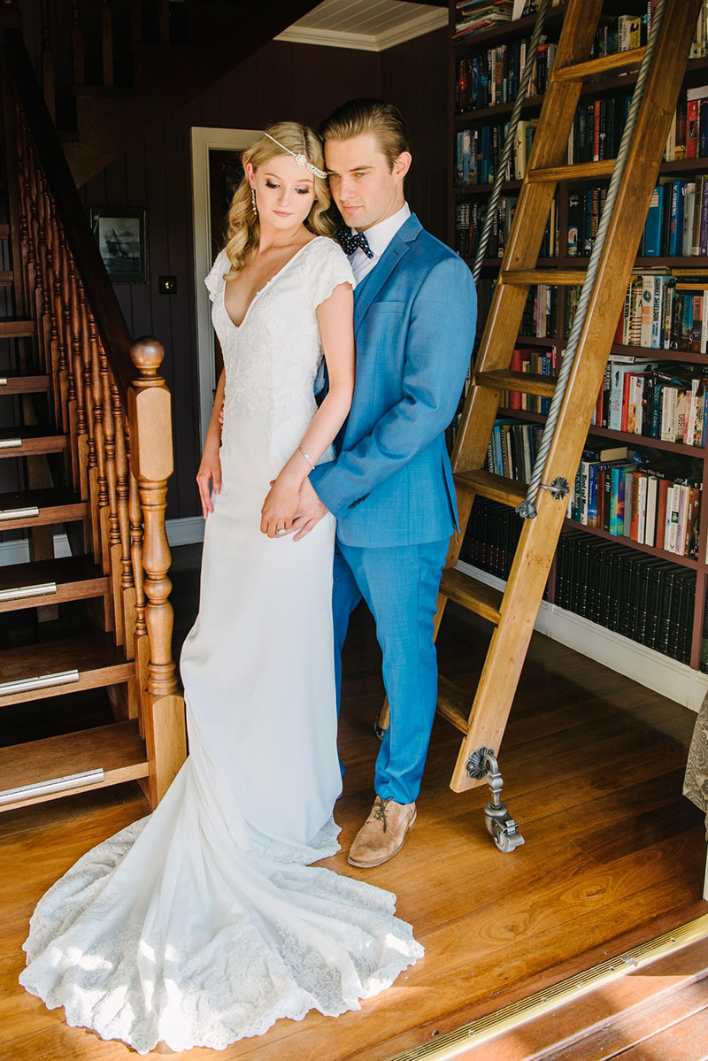 Bride wearing a v-necked wedding gown with groom wearing a blue suit.