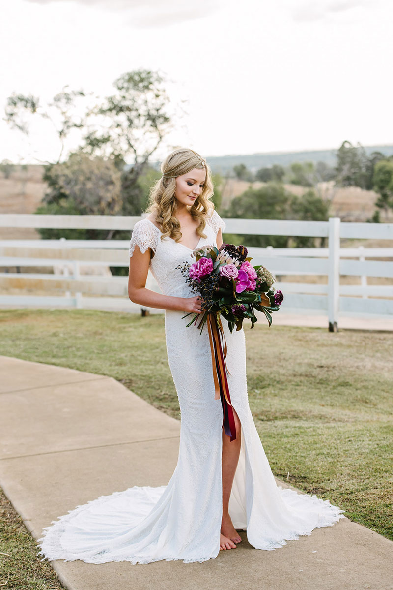 Bride in wedding gown holding large bouquet of flowers. 